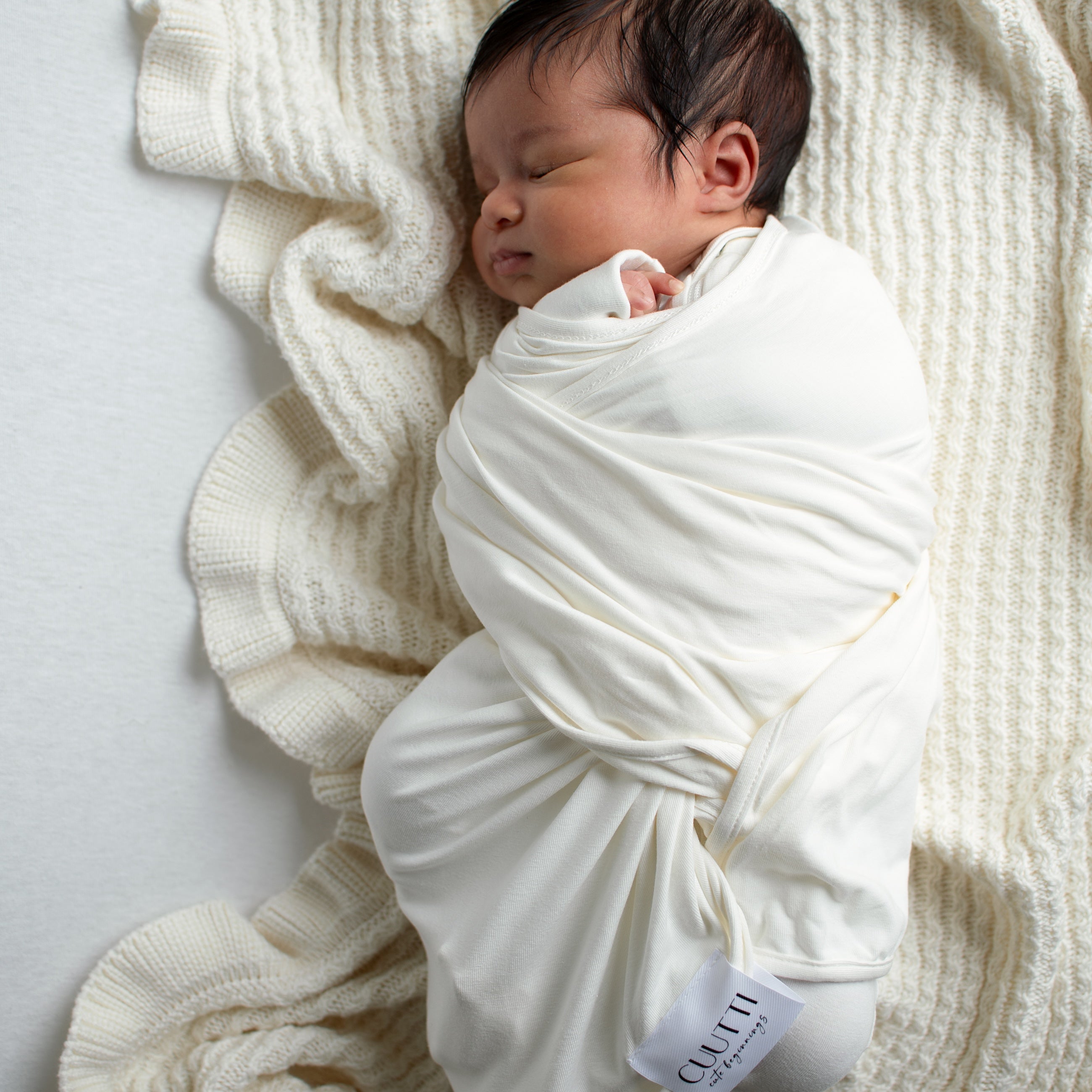 1-month-old baby boy wrapped in an ivory CUUTTI baby swaddle.