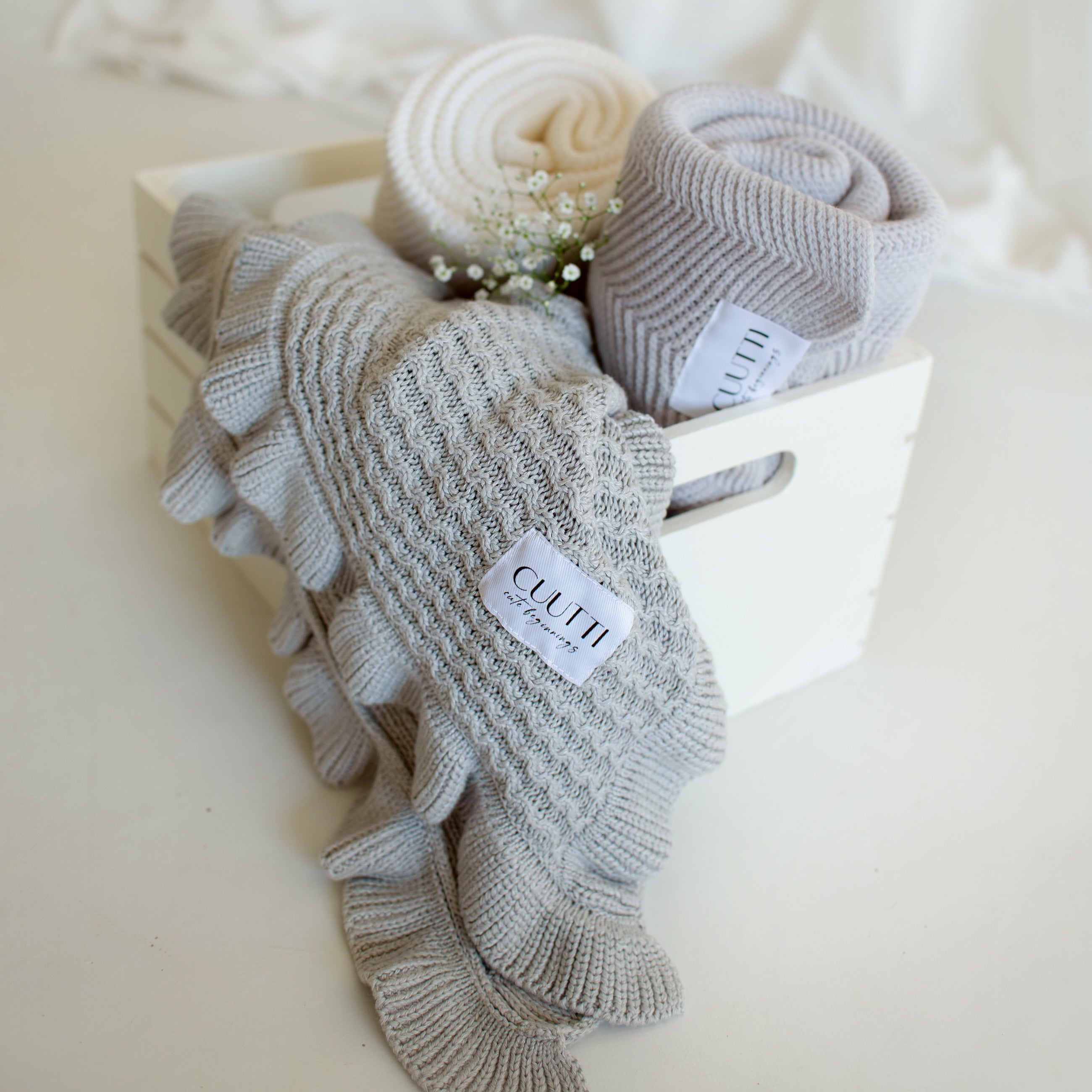 A small box filled with three CUUTTI blankets, highlighting the cloud color CUUTTI Ballerina bamboo blanket in the front.