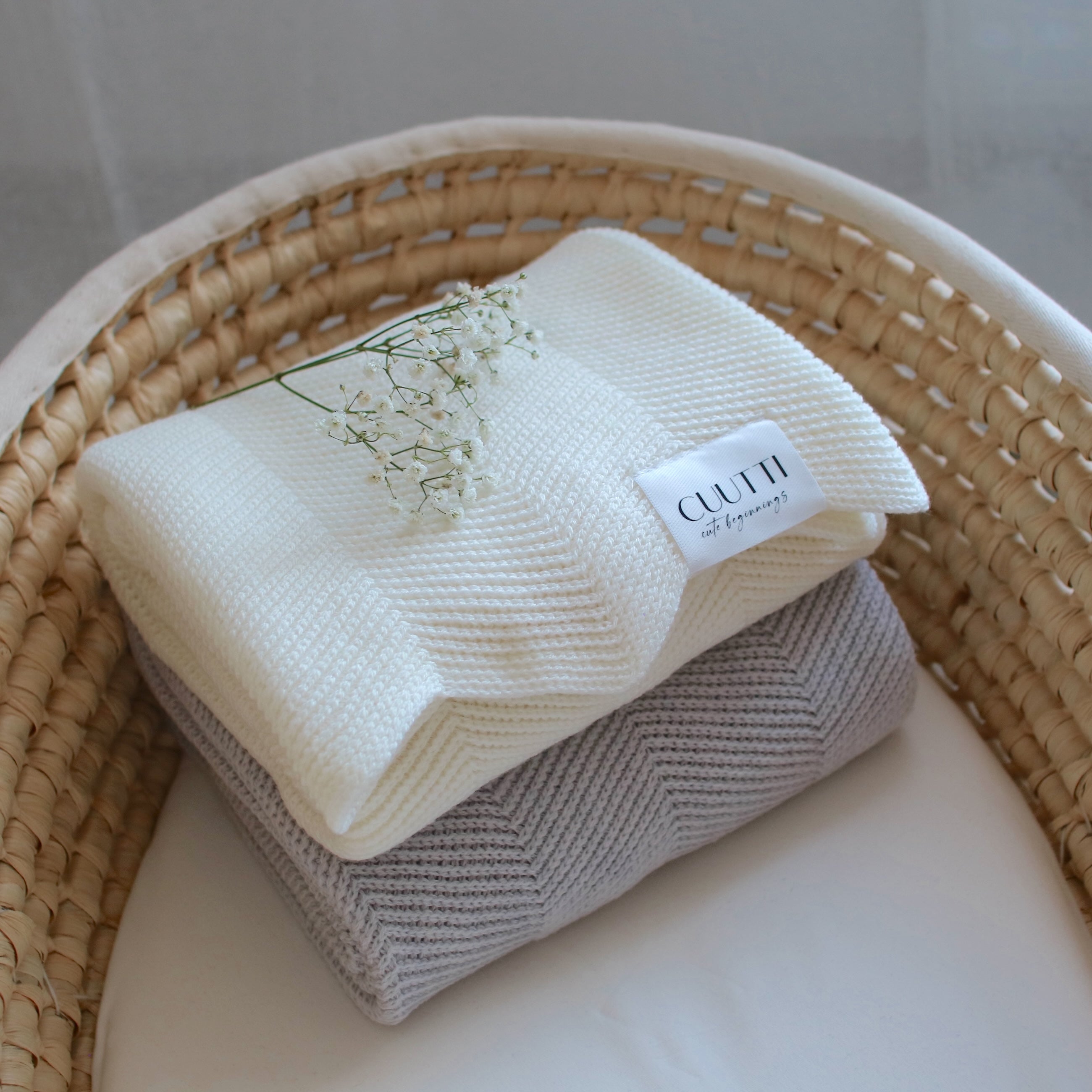 CUUTTI 100% merino wool Harmony blankets in ivory and cloud color, neatly folded in a basket.