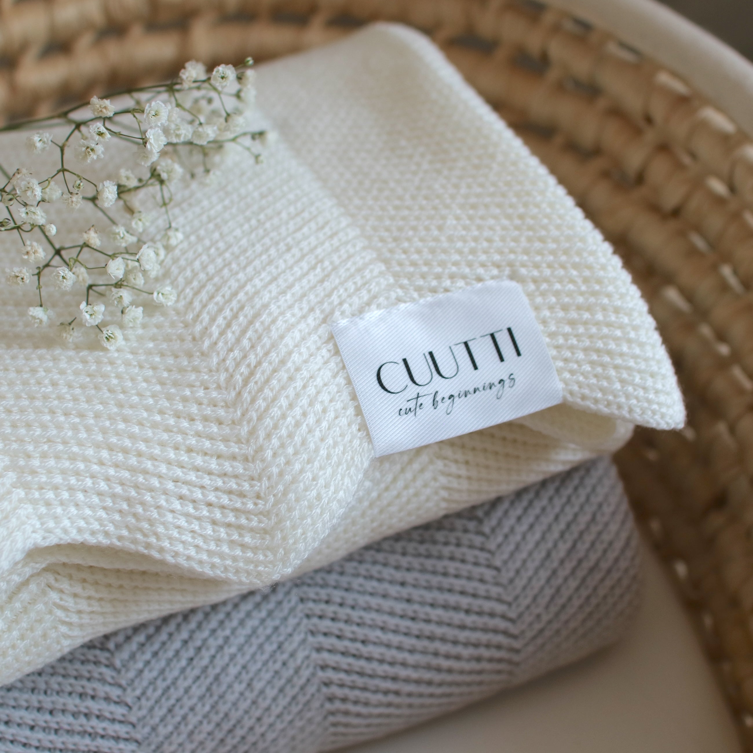 Close-up of CUUTTI 100% merino wool Harmony blankets in ivory and cloud color, neatly folded in a basket.