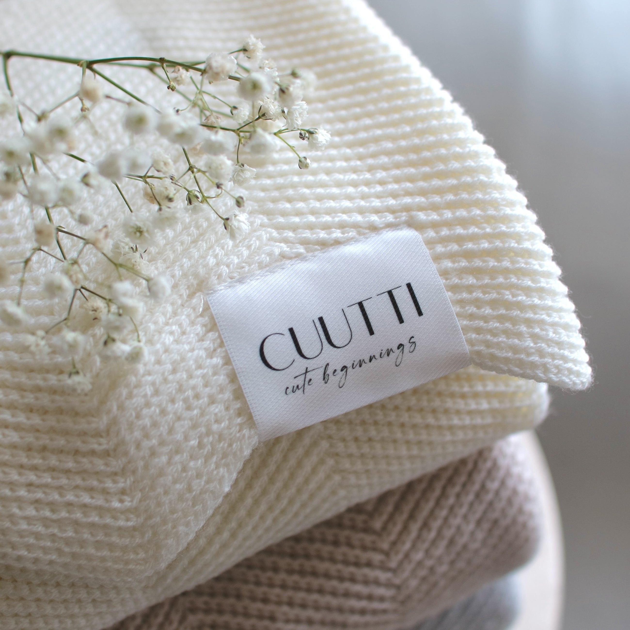 Close-up of CUUTTI 100% merino wool Harmony blanket in ivory, highlighting the knitting pattern.