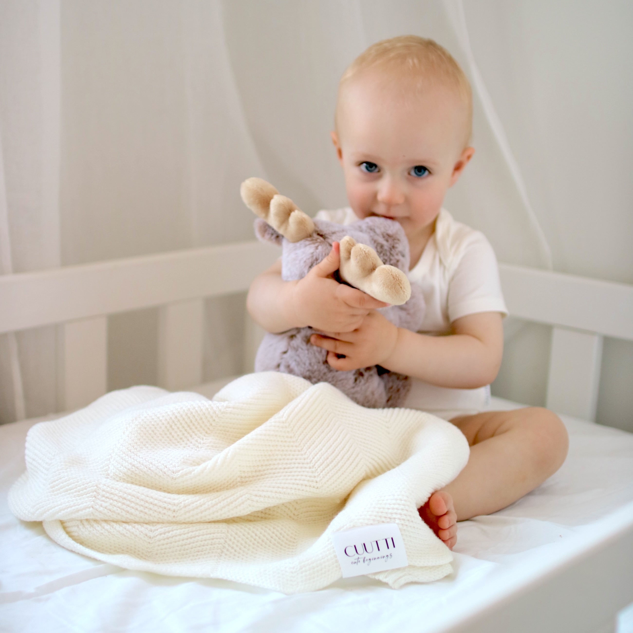 CUUTTI 100% merino wool Harmony blanket in ivory, providing warmth and comfort for a toddler boy on his bed.